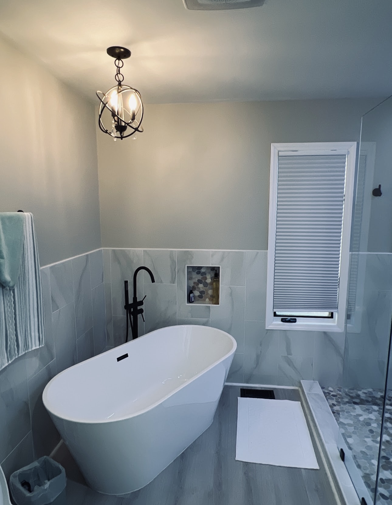Finished bathroom with a freestanding tub, soft blue walls, and marble-look tile