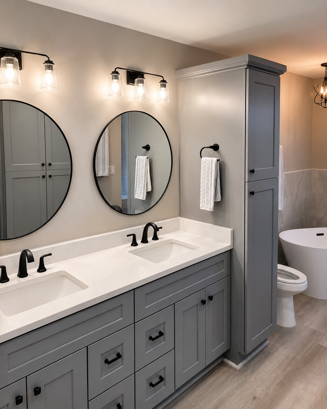 Finished bathroom with gray double vanity, round mirrors, and freestanding tub